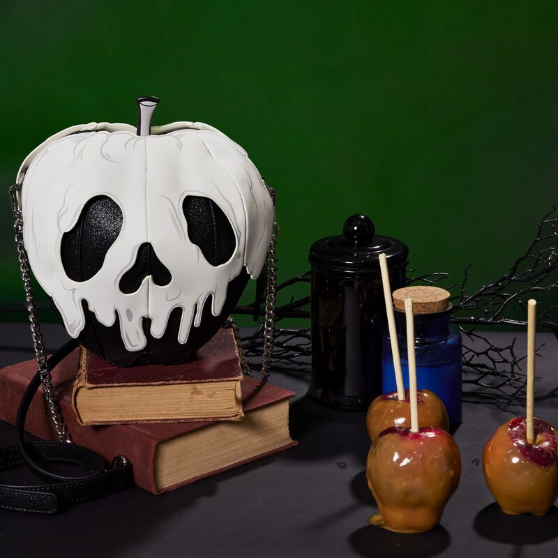 Image of our Black and White Poison Apple Crossbody sitting on two books next to caramel apples